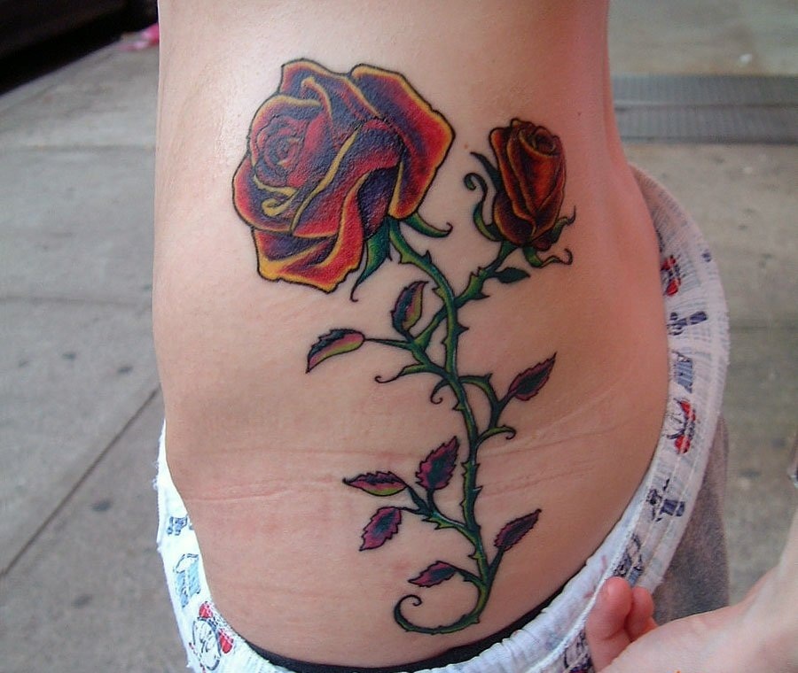 Цветная роза с шипами на боку у девушки