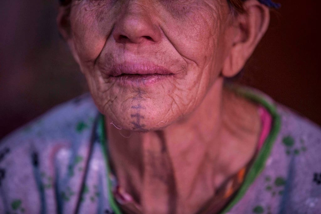 In this Saturday, October 13, 2018 photo, Hadda Oaabjde, 71, poses for a portrait displaying her face tattoo, in the town of Tinguerf, near Azilal, central Morocco. In Morocco