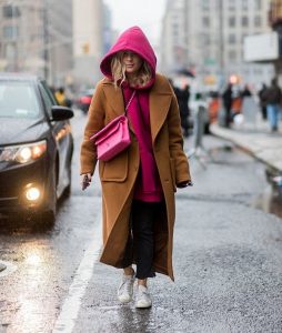 Девушка в длинном коричневом пальто и с розовой сумкой через плечо