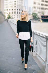 Девушка в коротком черном свитере и белой блузке