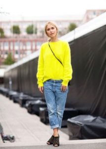 Девушка блондинка в джинсах светлого оттенка и в яркой желтой кофте