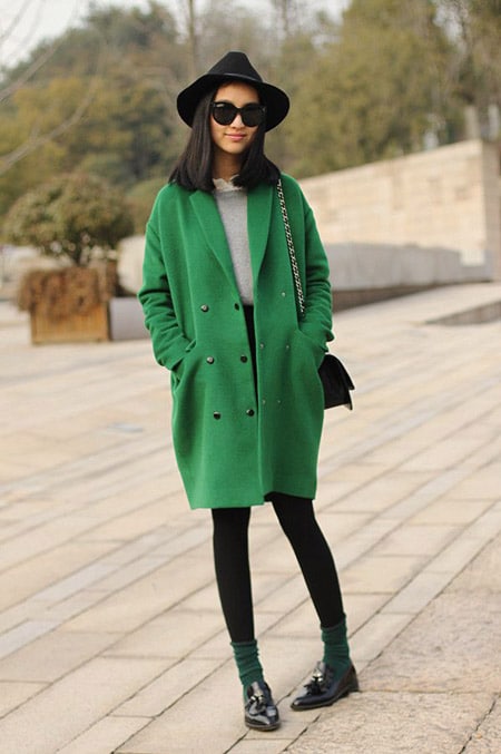 Девушка в ярком зеленом пальто и шляпе