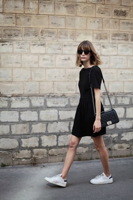 Модель в черном платье с коротким рукавом, сумочка и белые кроссовки