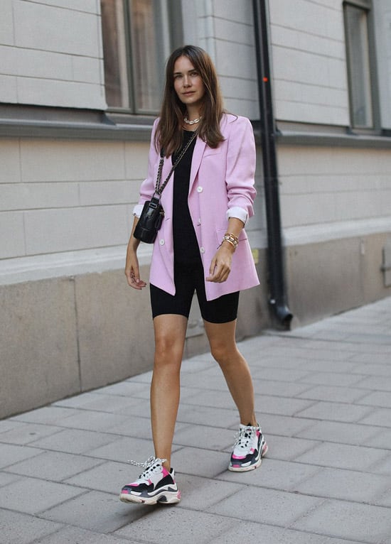 Девушка в велосипедных шортах, розовый блейзер и кроссовки