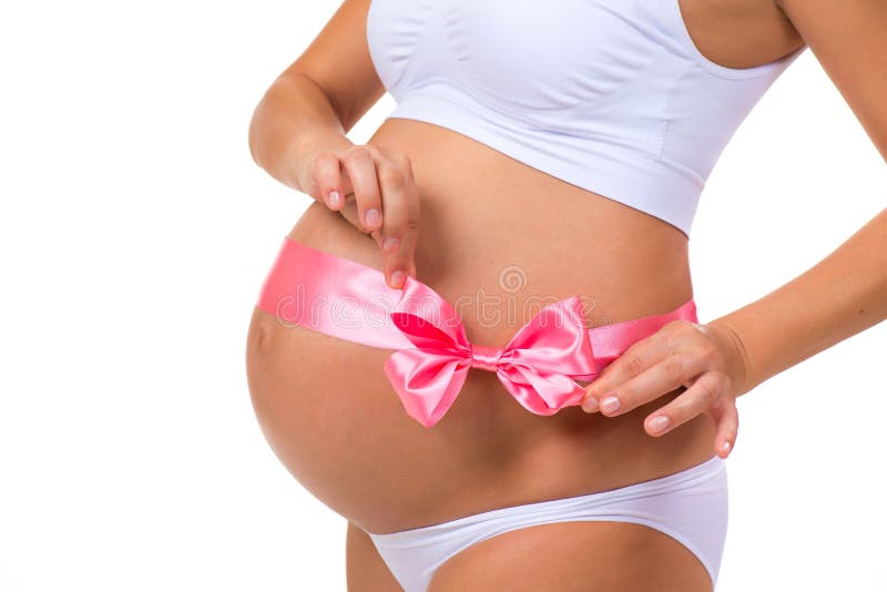 Close-up of pregnant belly with pink ribbon bow for newborn baby girl. Concept of pregnancy royalty free stock photo