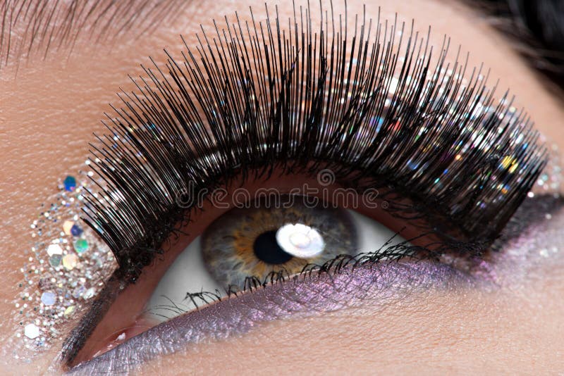 Eye with long black false eyelashes and creative fashion makeup. Closeup woman