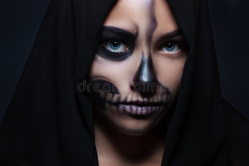 Halloween. Portrait of a young beautiful girl with skeleton makeup on her face. Girl in black hood face closeup royalty free stock photo