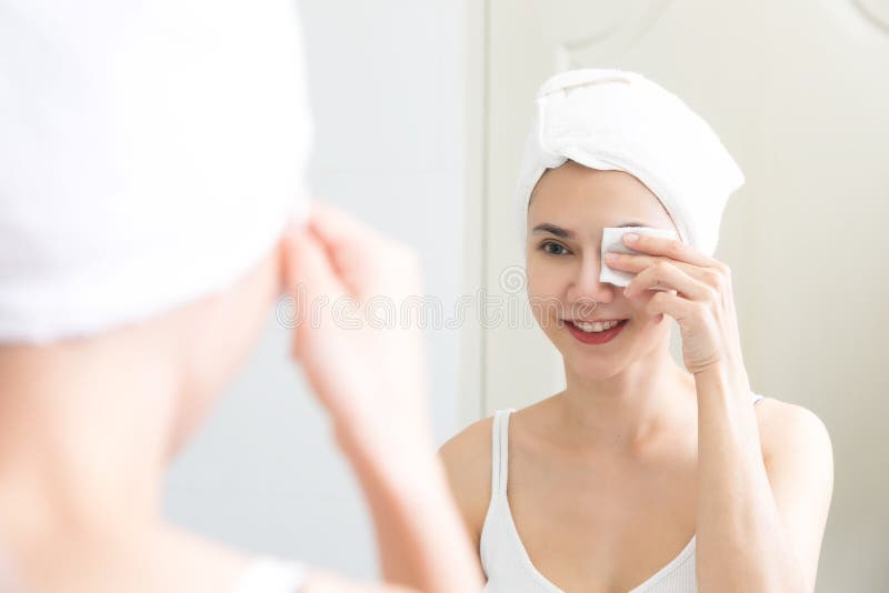 Healthy fresh girl removing makeup from her face with cotton pad. Skin care and beauty concept stock photos