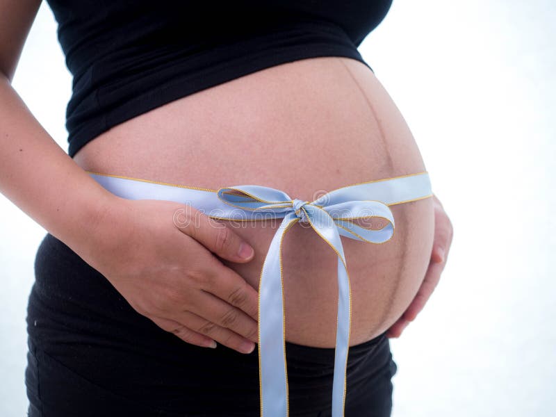 Image of pregnant woman touching her belly with a bow tie.  royalty free stock image