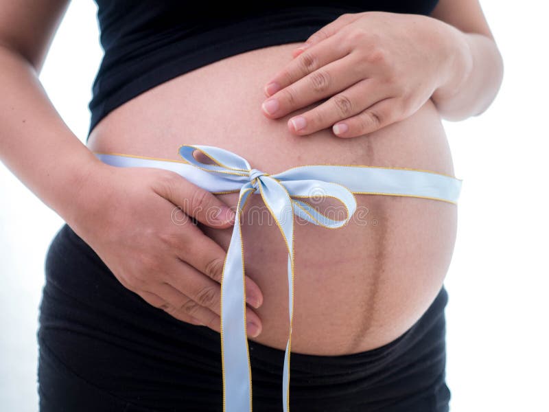 Image of pregnant woman touching her belly with a bow tie.  stock photo