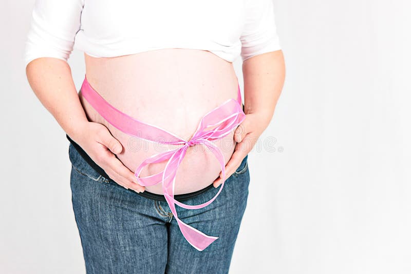 Pink bow around pregnant woman. Pink bow around exposed stomach of pregnant woman, white background stock image