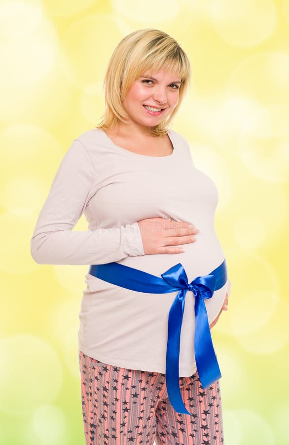 Pregnant woman with blue bow. On yellow background stock photo