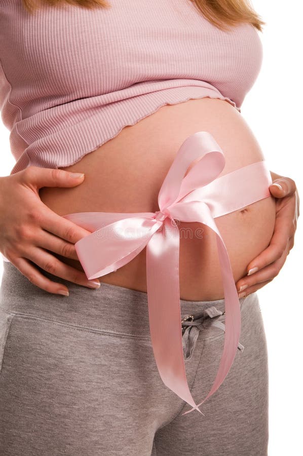 Pregnant woman expecting a baby girl. With pink bow on her belly royalty free stock image