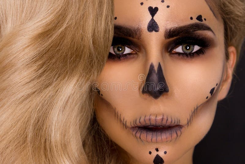 Blonde woman in Halloween makeup and leather outfit on a black background in the studio. Skeleton, monster. Blonde woman model in Halloween makeup and leather stock images
