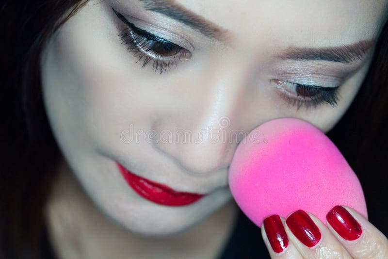 Woman Applying makeup. Using beauty blender stock photos