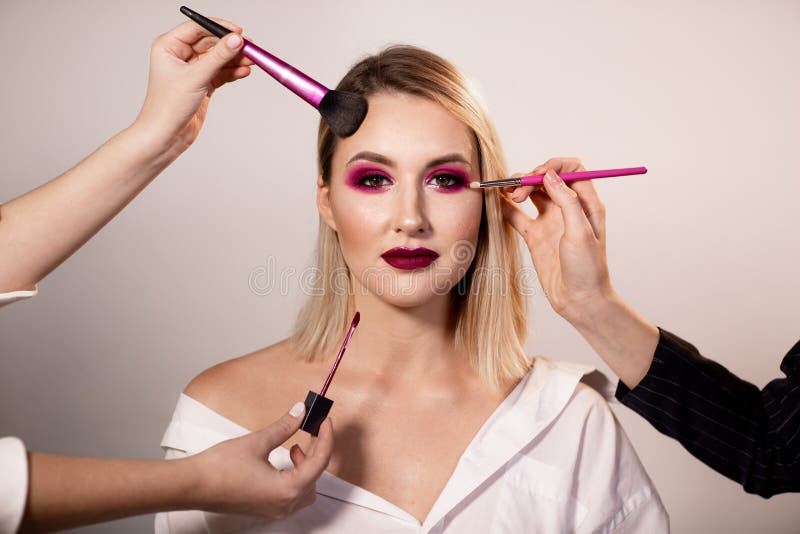 Young woman with bright pink makeup posing in light studio background. Professional makeup stock image